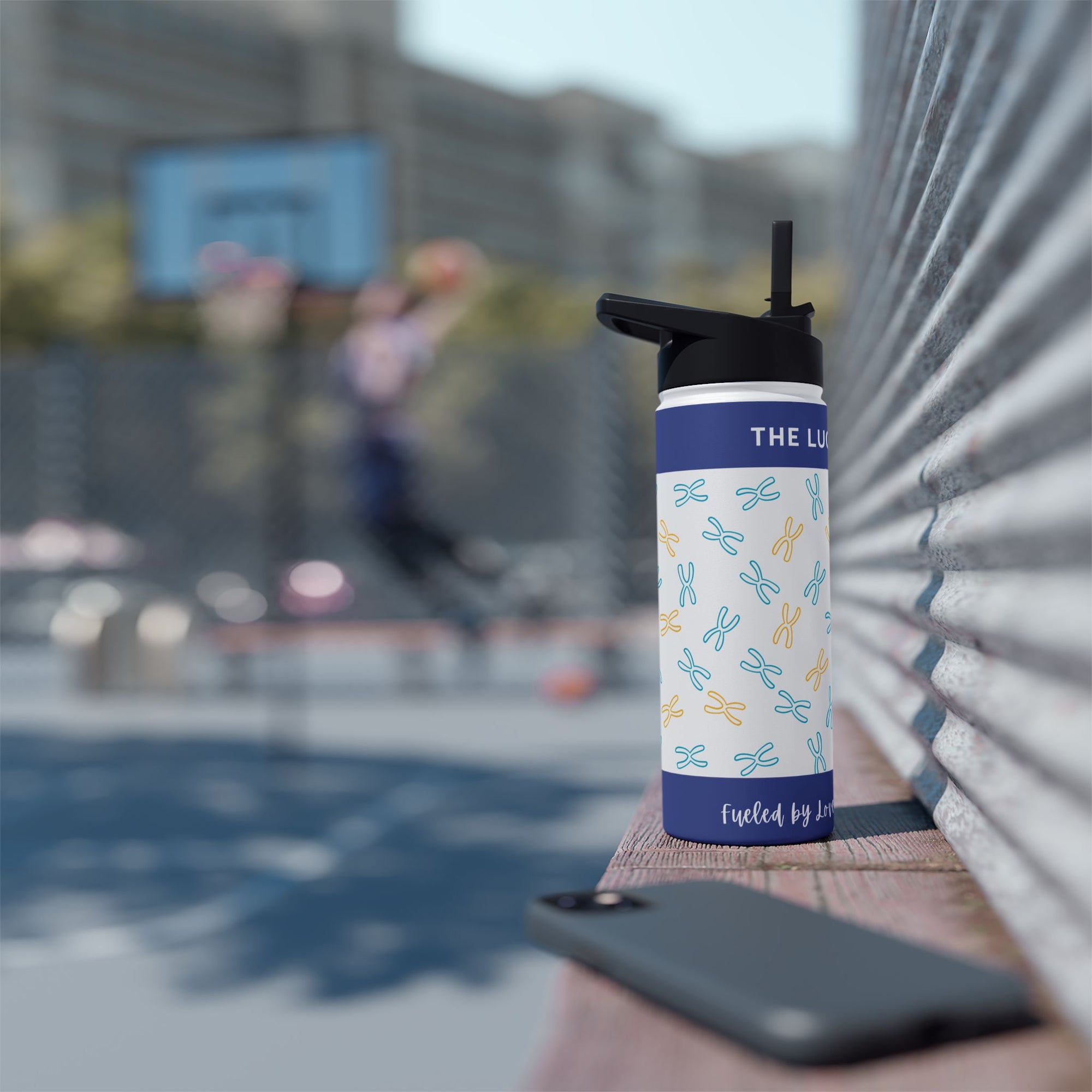 Blue and white patterned water bottle with black lid and straw on bench.
